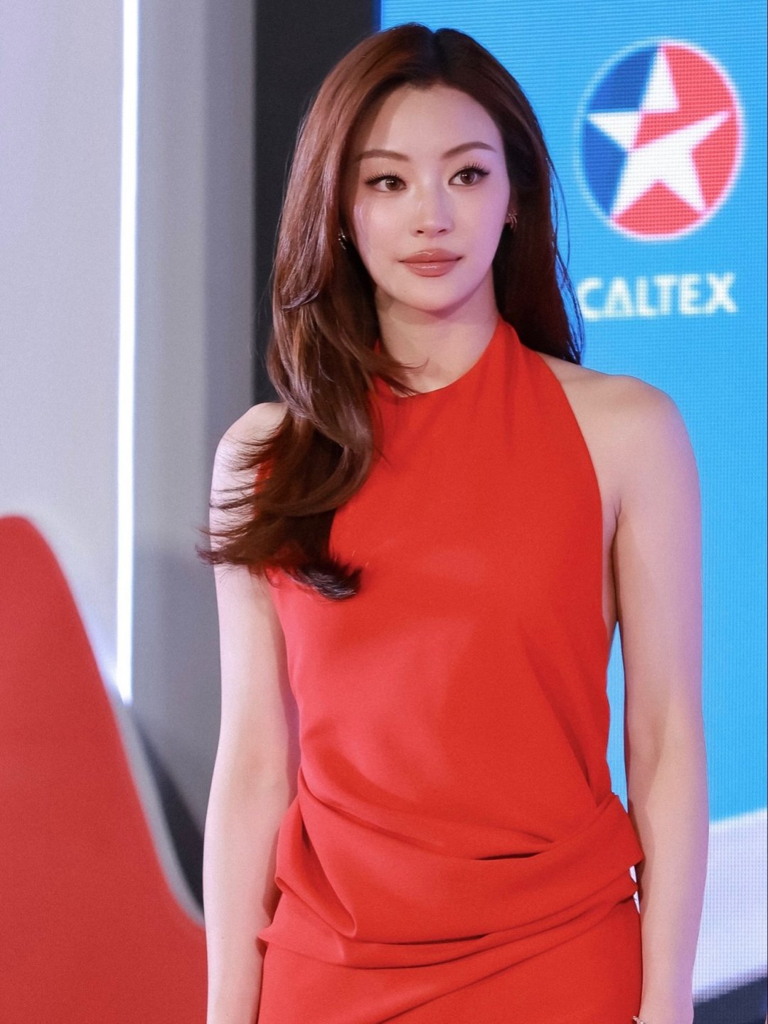 Natsha T. เดรสแดงคล้องคอเว้าแขน "มาเก็บดาวกับ CALTEX" ยืนถือไมค์บนเวทีงานเปิดตัว