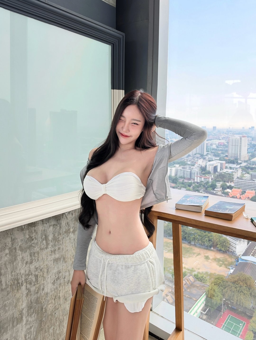 Viewvy เกาะอกขาวคู่กางเกงขาสั้นสีเทา คาร์ดิแกนเทาอ่อน นั่งอ่านหนังสือในห้องกระจกวิวตึกสูง