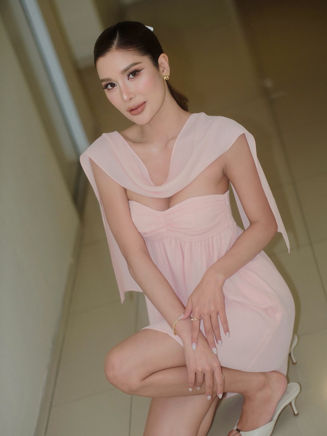 THAMITA ANUSIN เดรสเกาะอกชมพูอ่อนพาดผ้าชีฟอง ผมหางม้าผูกโบว์ขาว โพสท่าในโถงทางเดิน