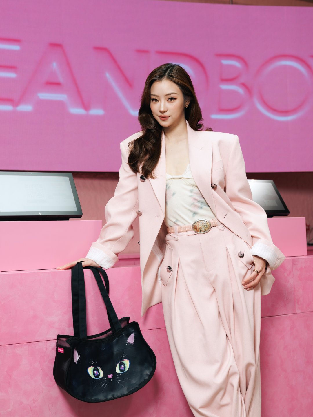Natsha T. สูทโอเวอร์ไซซ์ชมพูพาสเทล ยิ้มหวานถือกระเป๋าแมวดำ งานเปิด EVEANDBOY Siam Square One