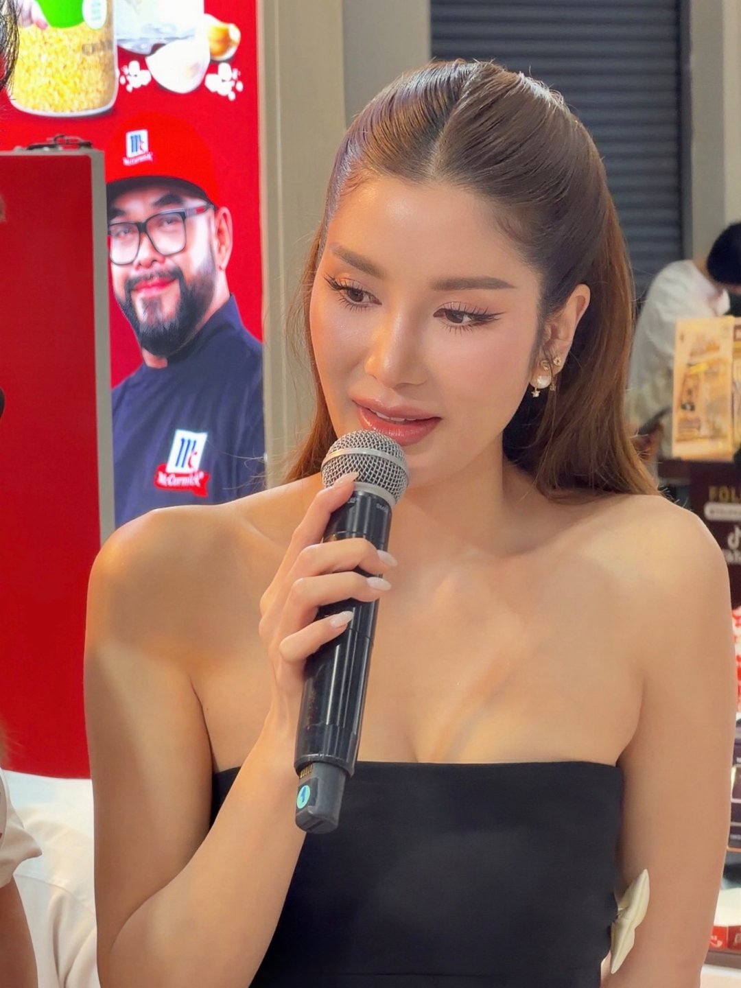 THAMITA ANUSIN เดรสเกาะอกดำผ่าข้างประดับโบว์ขาว ถือไมค์เป็นพิธีกรบูธ McCormick งาน HeReCa 2026 (รูปที่ 2)
